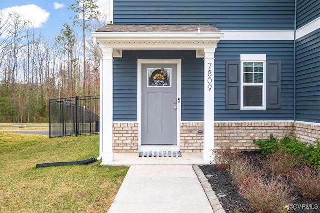 view of exterior entry with a yard and brick siding