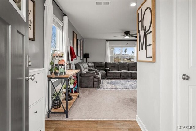 living room featuring light wood-type flooring, visible vents, and a ceiling fan