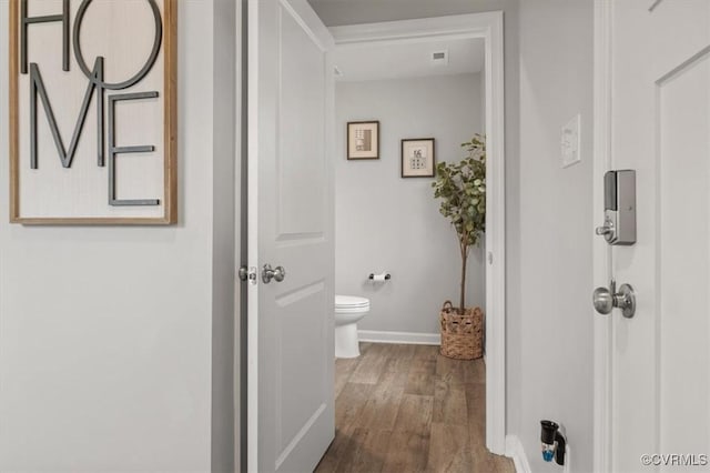 corridor featuring visible vents, baseboards, and wood finished floors