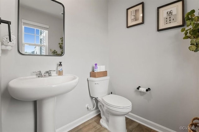 bathroom featuring toilet, wood finished floors, and baseboards