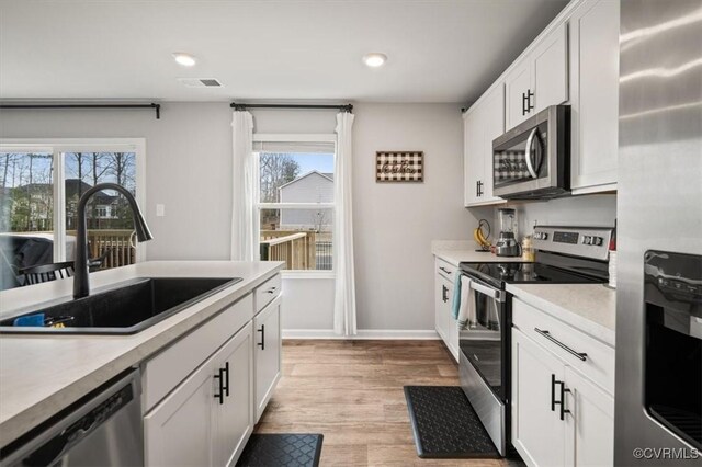 kitchen with visible vents, a sink, light countertops, white cabinets, and appliances with stainless steel finishes