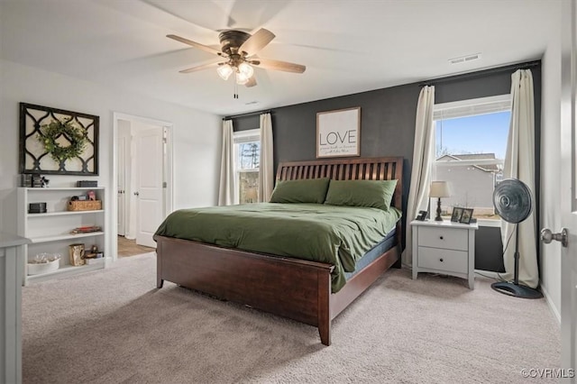 bedroom with a ceiling fan, visible vents, and light carpet