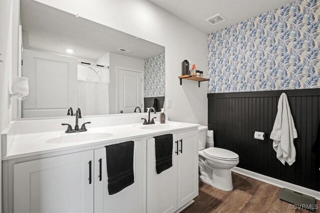 bathroom with toilet, wainscoting, visible vents, and a sink