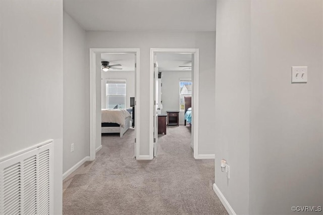 hallway featuring baseboards, visible vents, and carpet floors