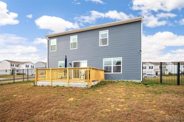 rear view of property with a lawn, a deck, and fence