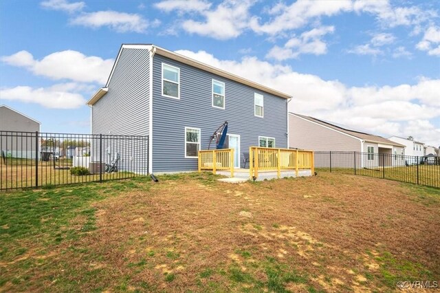 rear view of house with a lawn, fence, and a wooden deck