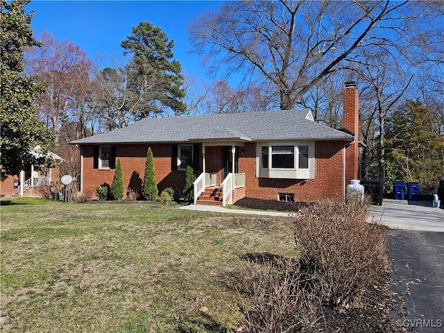 ranch-style house featuring brick siding, a chimney, and a front yard