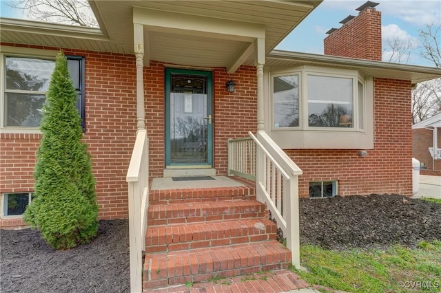 doorway to property with brick siding and a chimney