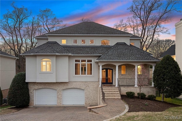 view of front of home with brick siding, a porch, stucco siding, french doors, and decorative driveway