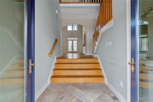 stairway featuring visible vents, arched walkways, and baseboards