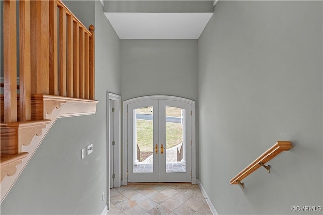 entryway with arched walkways, french doors, stairs, and baseboards