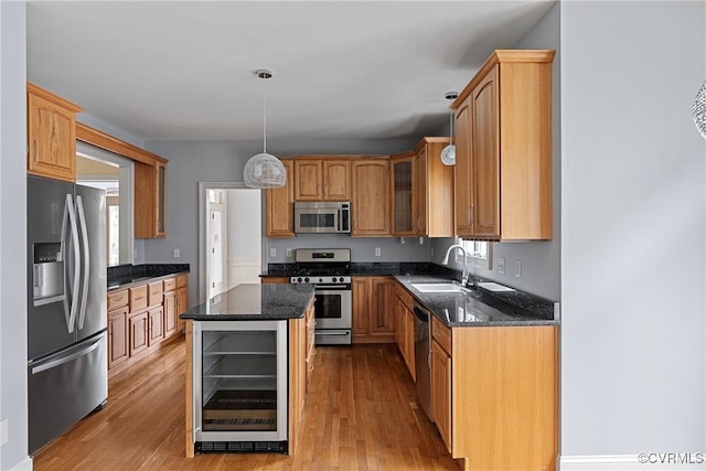 kitchen with beverage cooler, dark stone countertops, stainless steel appliances, and a sink