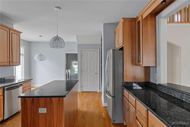 kitchen featuring hanging light fixtures, light wood finished floors, appliances with stainless steel finishes, and a kitchen island