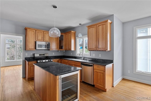 kitchen with wine cooler, a healthy amount of sunlight, appliances with stainless steel finishes, and light wood-type flooring