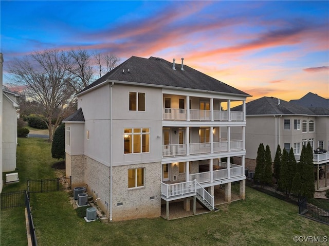 rear view of property featuring stairway, a balcony, fence, crawl space, and a lawn