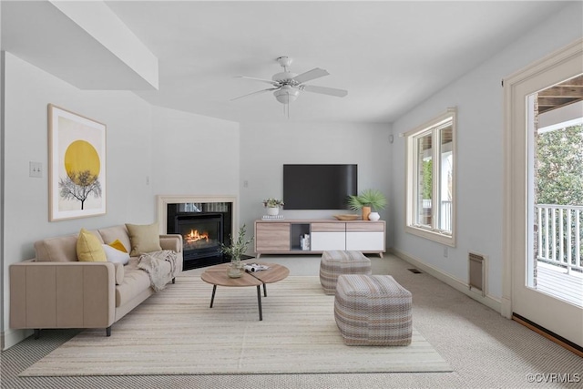 carpeted living room with visible vents, baseboards, ceiling fan, and a fireplace