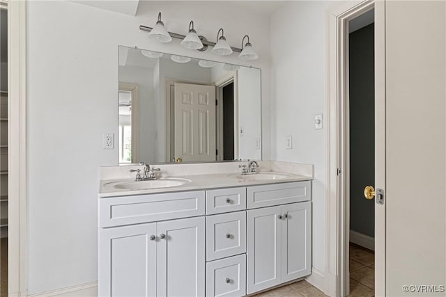 bathroom featuring tile patterned flooring, double vanity, baseboards, and a sink