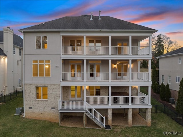 back of property at dusk featuring crawl space, a yard, and a balcony