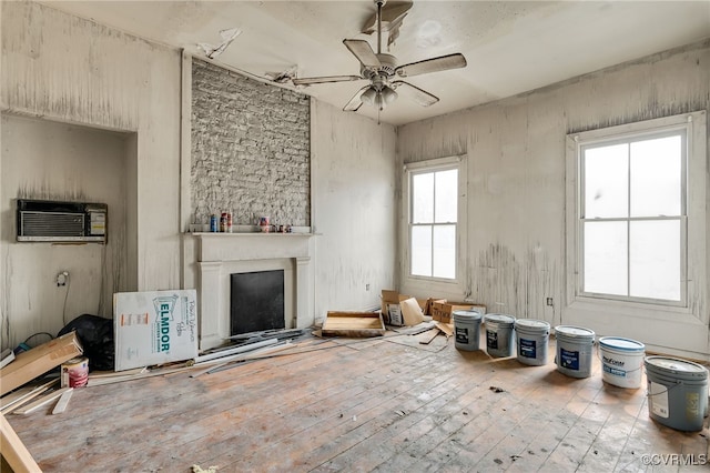 unfurnished living room with a ceiling fan, an AC wall unit, a fireplace, and hardwood / wood-style flooring