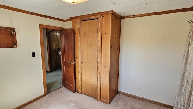 unfurnished bedroom featuring a closet, light carpet, baseboards, and ornamental molding