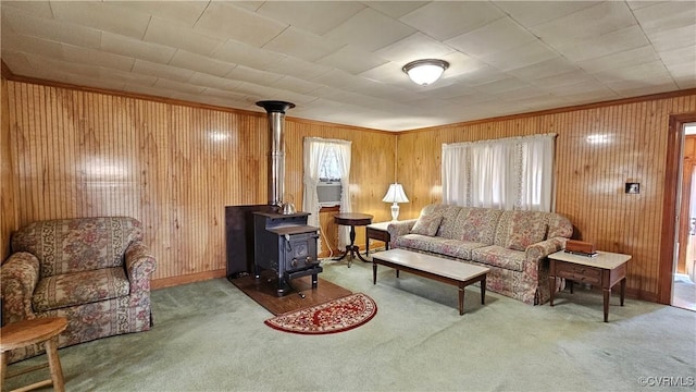 living room with crown molding, a wood stove, carpet, and wood walls