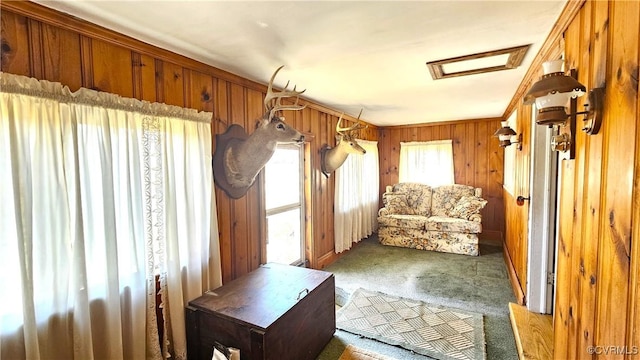 interior space featuring carpet floors, wooden walls, and attic access