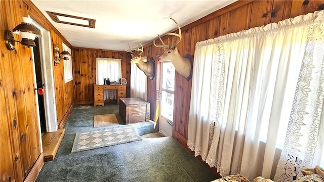 foyer with carpet floors and wood walls