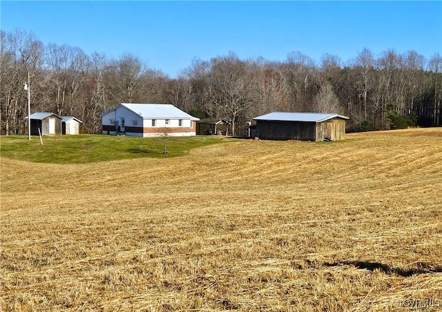 view of yard featuring a view of trees, an outdoor structure, and a pole building