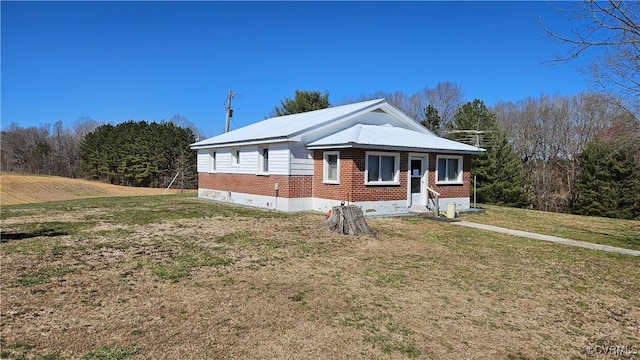 view of front of home with brick siding, metal roof, and a front yard