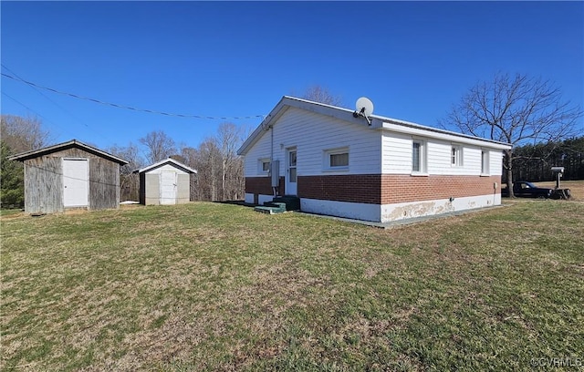 view of home's exterior featuring brick siding, entry steps, a lawn, an outdoor structure, and a storage unit