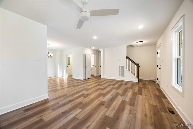 unfurnished living room featuring stairway, wood finished floors, visible vents, and baseboards