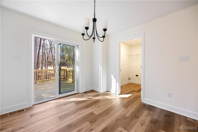 unfurnished dining area featuring a chandelier, visible vents, baseboards, and wood finished floors