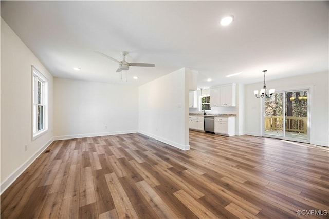 unfurnished living room with recessed lighting, baseboards, wood finished floors, and ceiling fan with notable chandelier