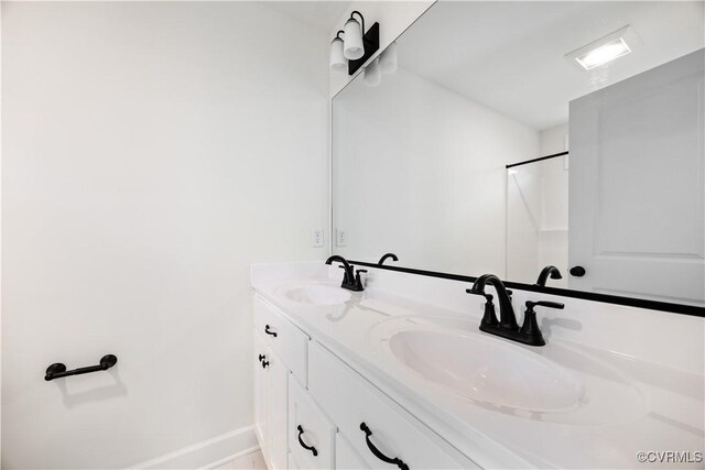 full bath featuring double vanity, baseboards, and a sink