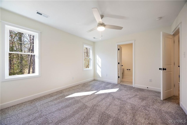 empty room featuring visible vents, light colored carpet, and baseboards