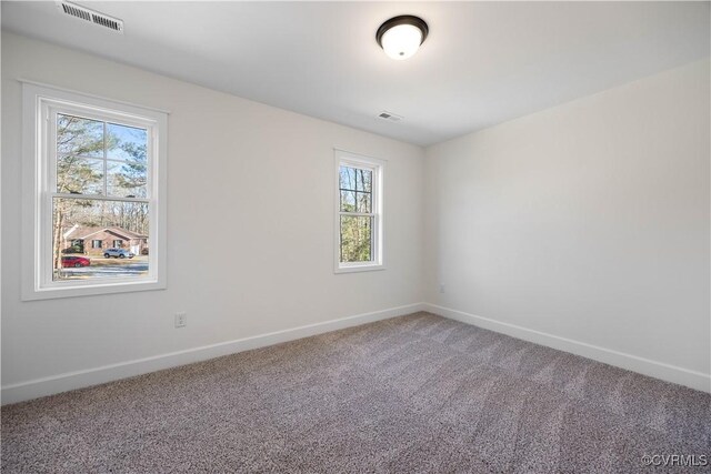 carpeted empty room featuring baseboards and visible vents