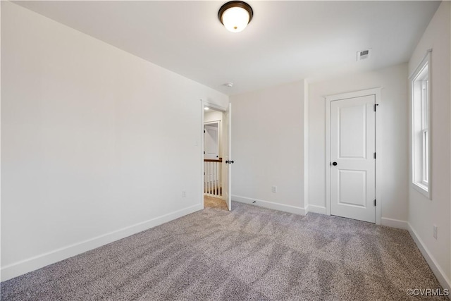 unfurnished room with light colored carpet, visible vents, and baseboards