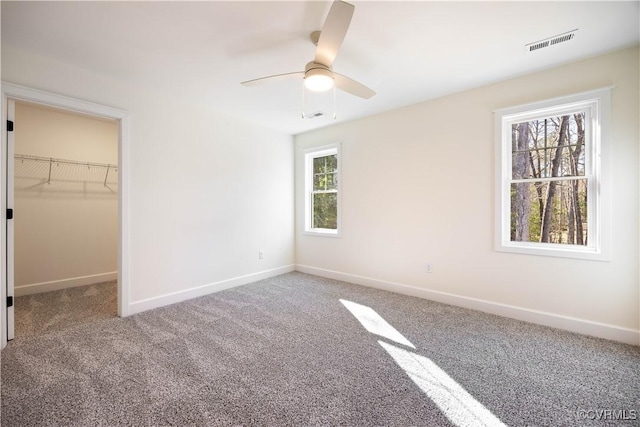 unfurnished bedroom with a ceiling fan, baseboards, visible vents, carpet floors, and a spacious closet