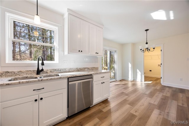 kitchen featuring white cabinetry, a sink, light wood-style floors, pendant lighting, and stainless steel dishwasher