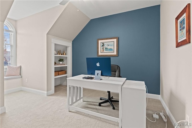 carpeted home office featuring built in shelves, baseboards, and vaulted ceiling