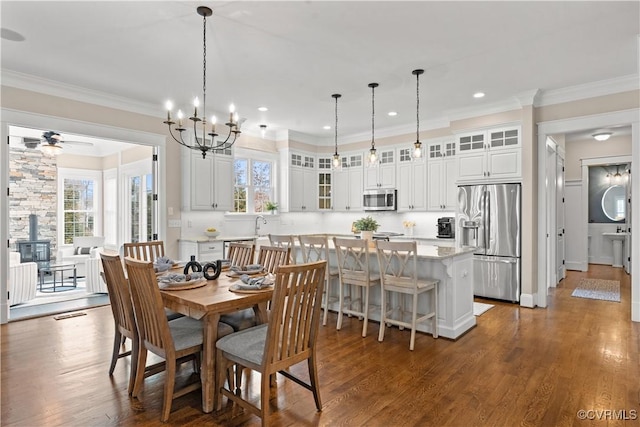 dining room with a wealth of natural light, wood finished floors, a wood stove, and ornamental molding