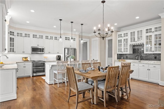 dining space with recessed lighting, wood finished floors, an inviting chandelier, and ornamental molding