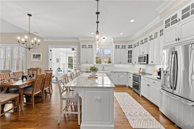 kitchen with a kitchen island, dark wood finished floors, a breakfast bar, appliances with stainless steel finishes, and white cabinets