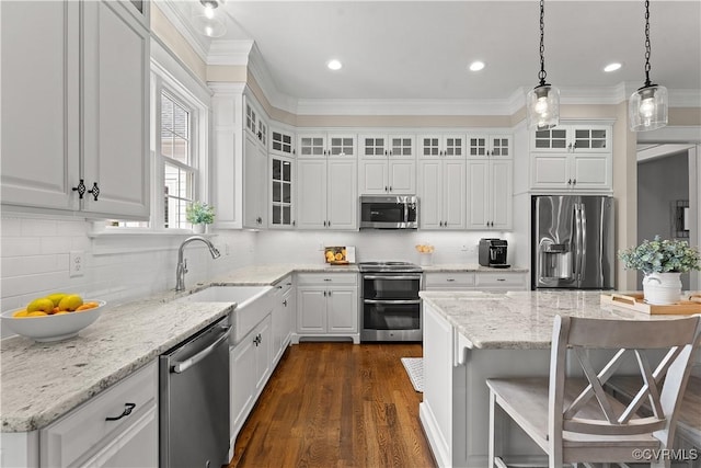 kitchen featuring dark wood finished floors, ornamental molding, stainless steel appliances, white cabinets, and pendant lighting