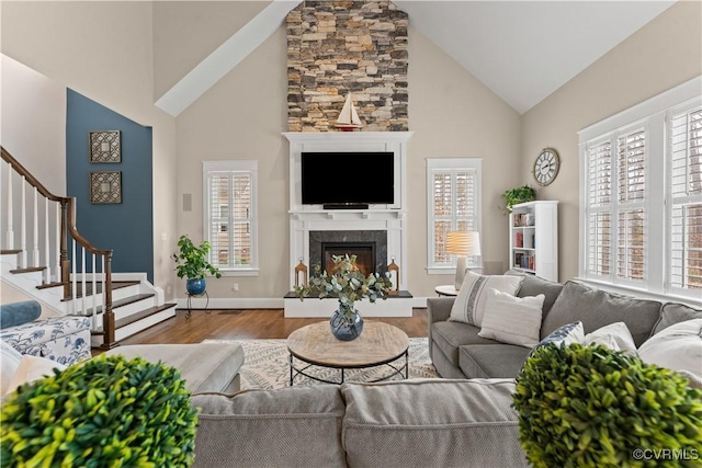 living room featuring high vaulted ceiling, wood finished floors, stairway, a fireplace, and baseboards