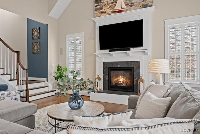 living area with a wealth of natural light, stairway, a fireplace, and wood finished floors