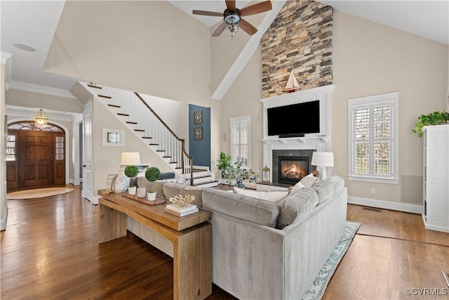 living room featuring visible vents, wood finished floors, stairway, a fireplace, and baseboards