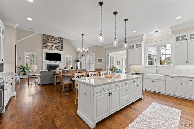 kitchen featuring a sink, a center island, a fireplace, white cabinetry, and dark wood-style flooring