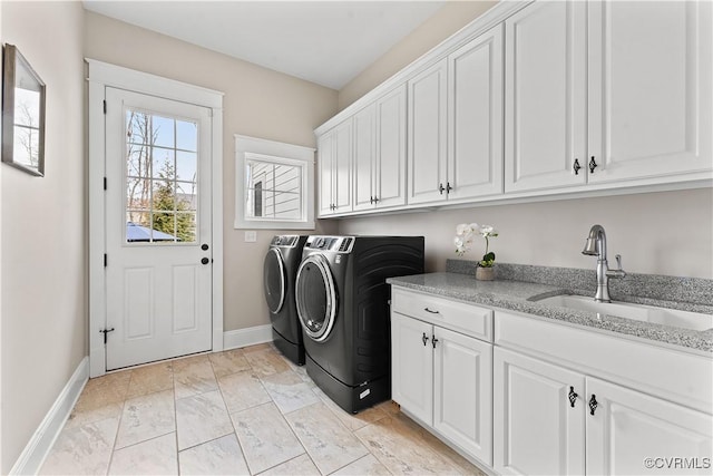 clothes washing area with washing machine and dryer, cabinet space, baseboards, and a sink