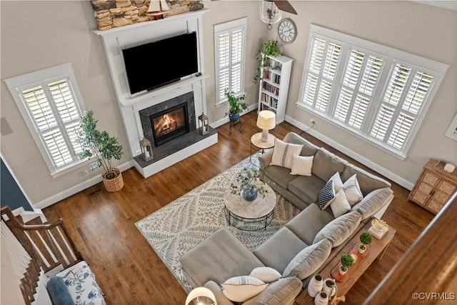 living room featuring a healthy amount of sunlight, a fireplace, baseboards, and wood finished floors